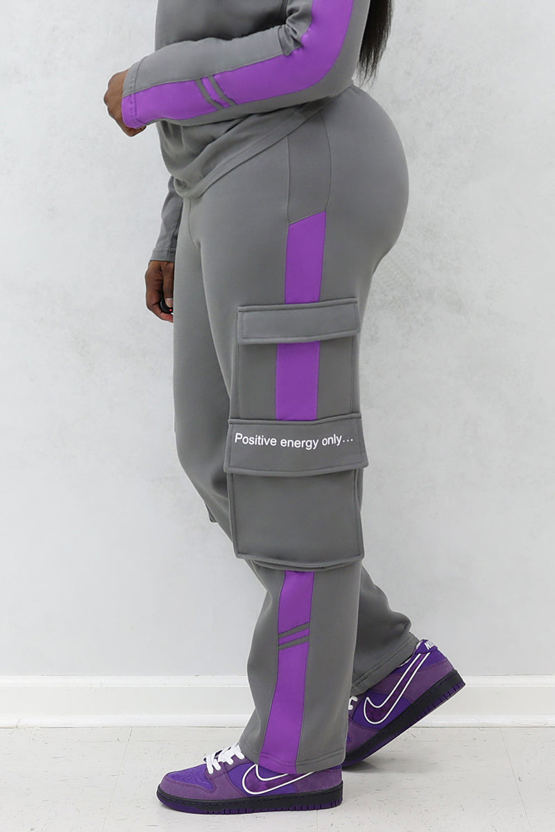A woman wearing gray and purple cargo joggers with pockets and purple Nike shoes
