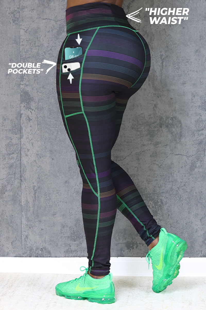 Wearing Sidelines High-Waisted Tights with green accents and green sneakers, a person stands by a gray wall. Arrows highlight the 4-way stretch waist and double pockets—one pocket holds a phone.