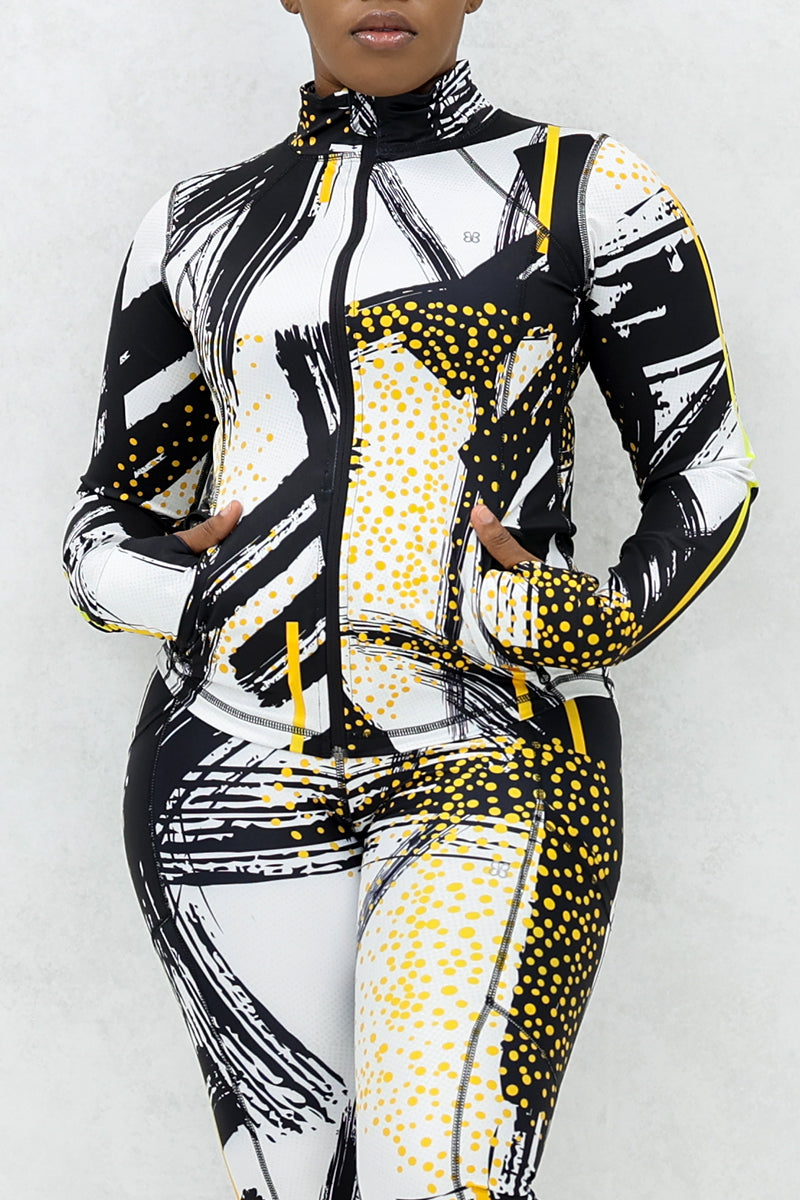 a woman wearing a fitted fitness jacket printed with a black, gold, and white abstract design.