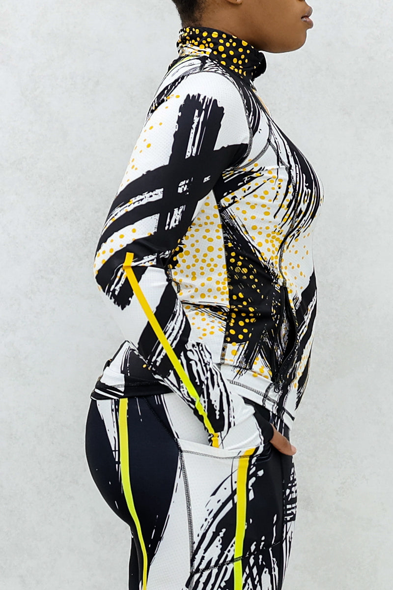 a woman wearing a fitted fitness jacket printed with a black, gold, and white abstract design.