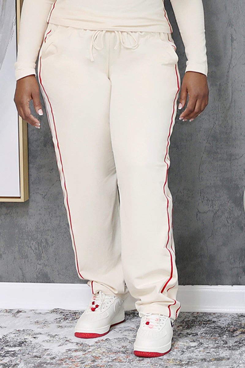 A woman wearing cream and red pants with a stylish design.