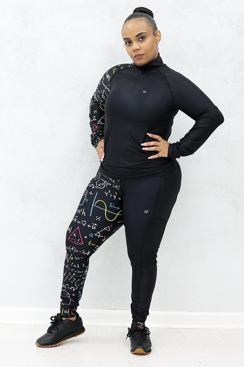 A woman wearing a black half-zip pullover and black tights both with multicolor math equations printed on one side and black shoes.