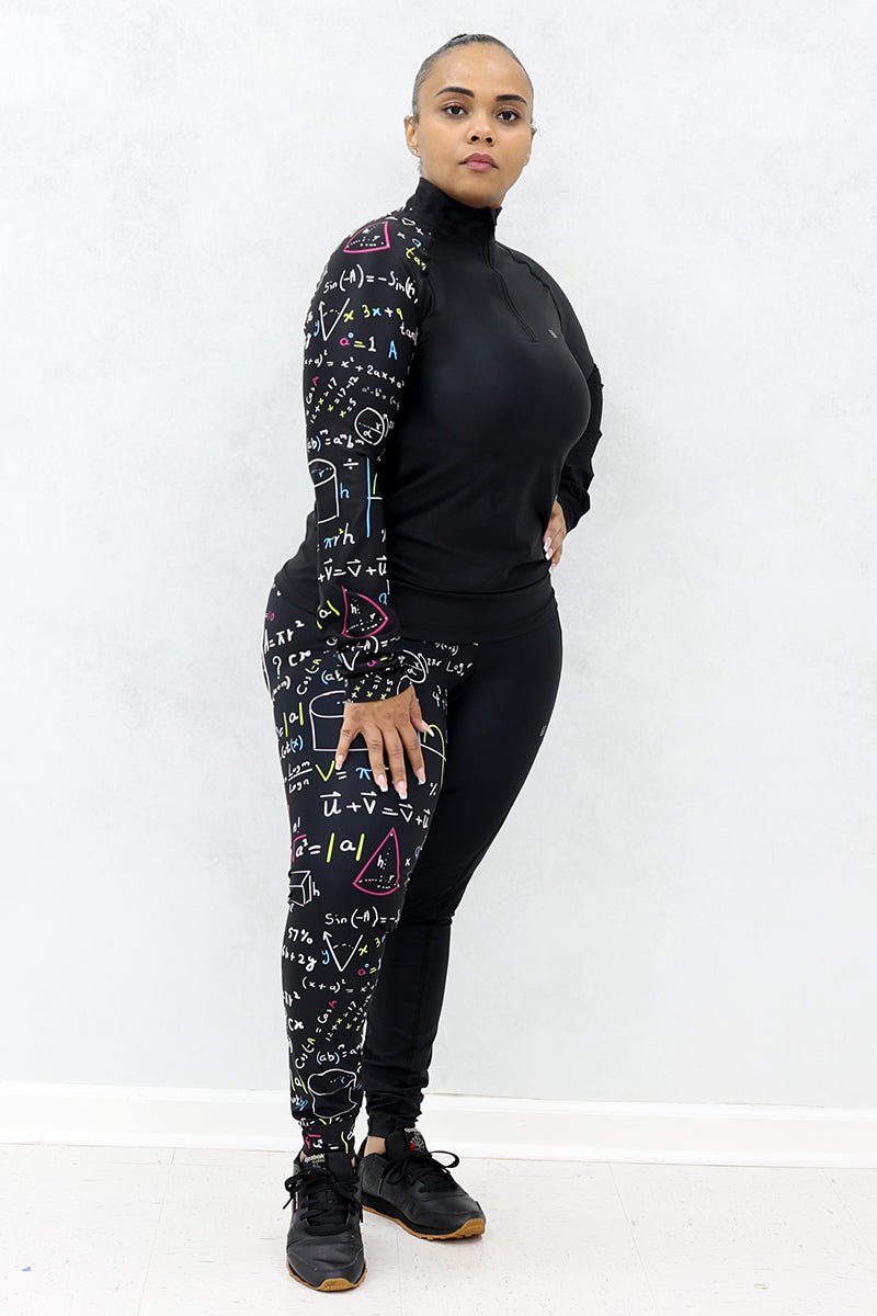 A woman wearing a black half-zip pullover and black tights both with multicolor math equations printed on one side and black shoes.