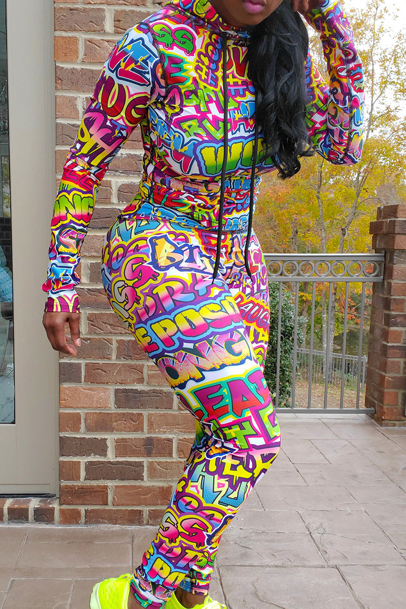 A woman wearing a multi-colored Graffiti hooded pullover with a unique design, perfect for workouts and casual wear.