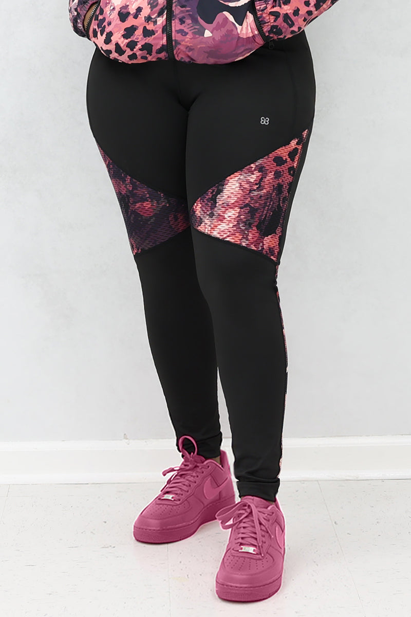 A woman wearing black and pink Graphic tights featuring printed panels and a continuous drawstring for a secure fit.