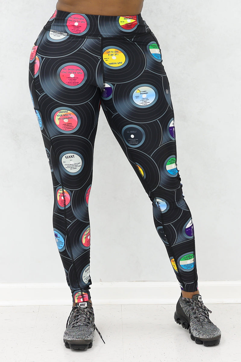 A woman wearing tights with vinyl record print and black sneakers.