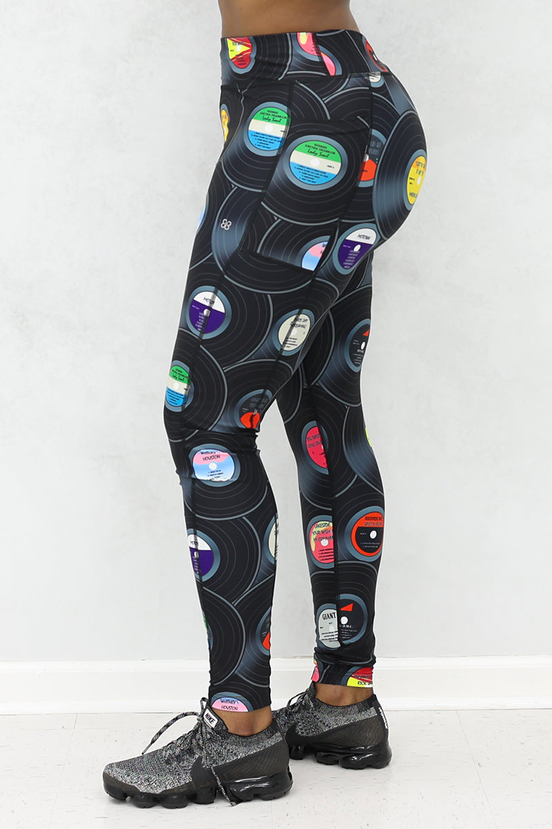 A woman wearing tights with vinyl record print, and black sneakers.