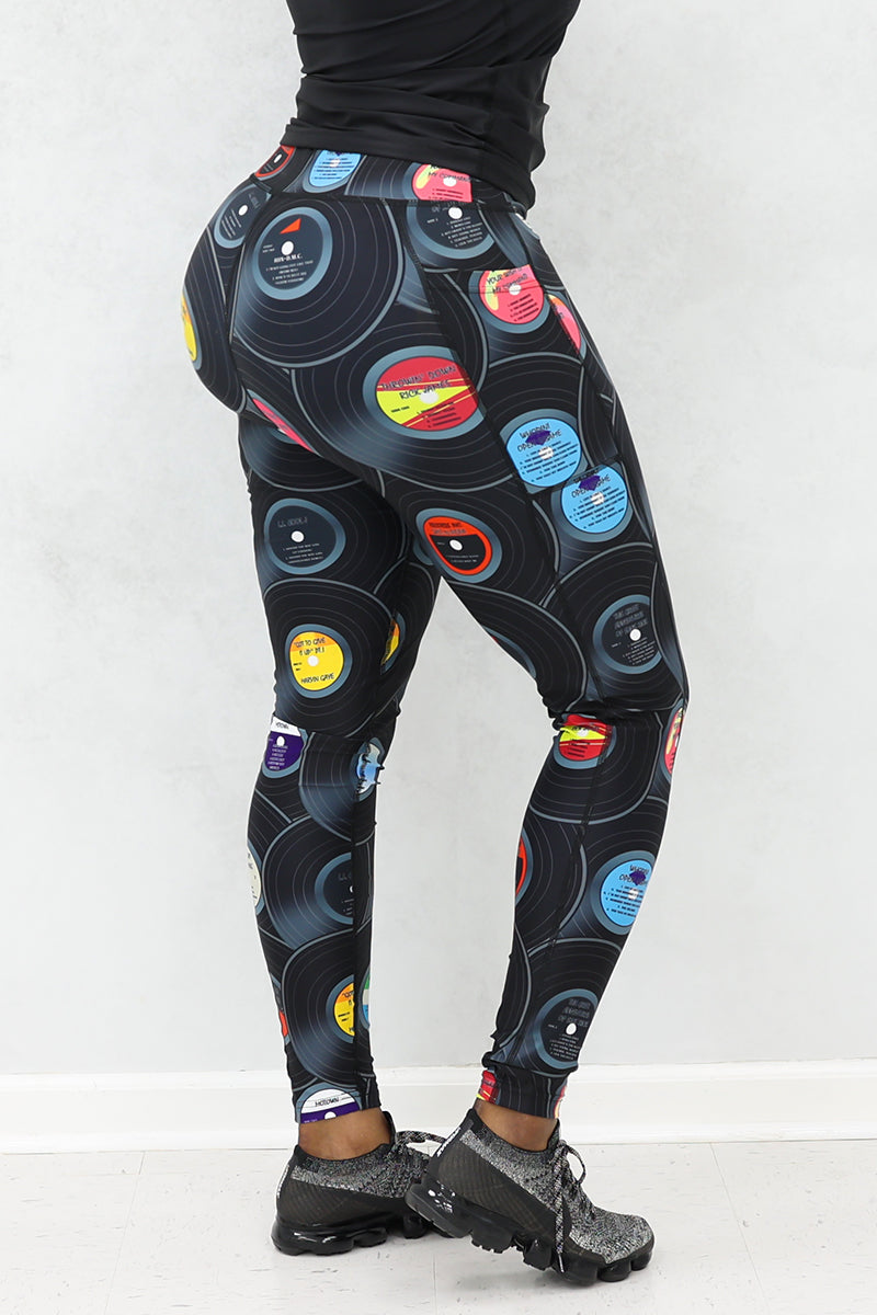 A woman wearing tights with vinyl record print, and black sneakers.