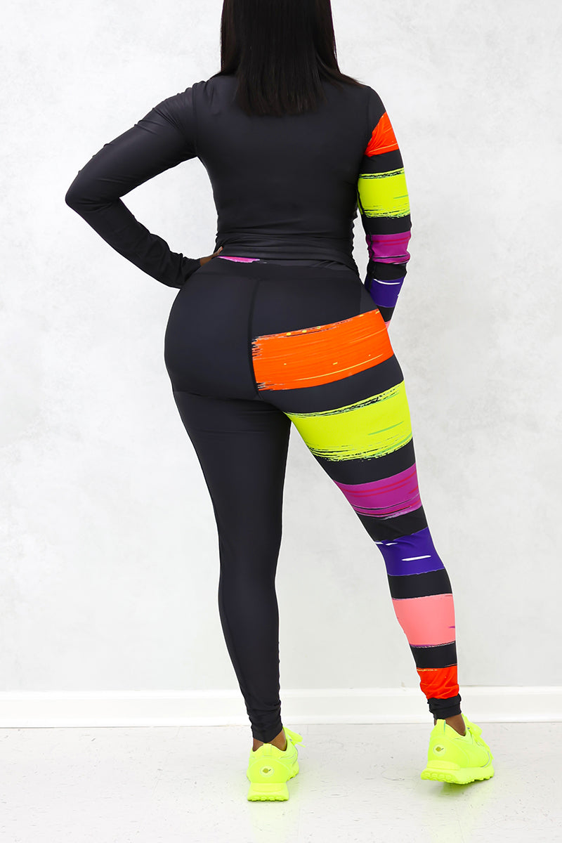 A woman wearing the Paint Strokes Half-Zip Pullover in vibrant multi colors, featuring a half zipper and a pocket on the left leg, showcasing a stylish blend of black, orange, lime, and purple.