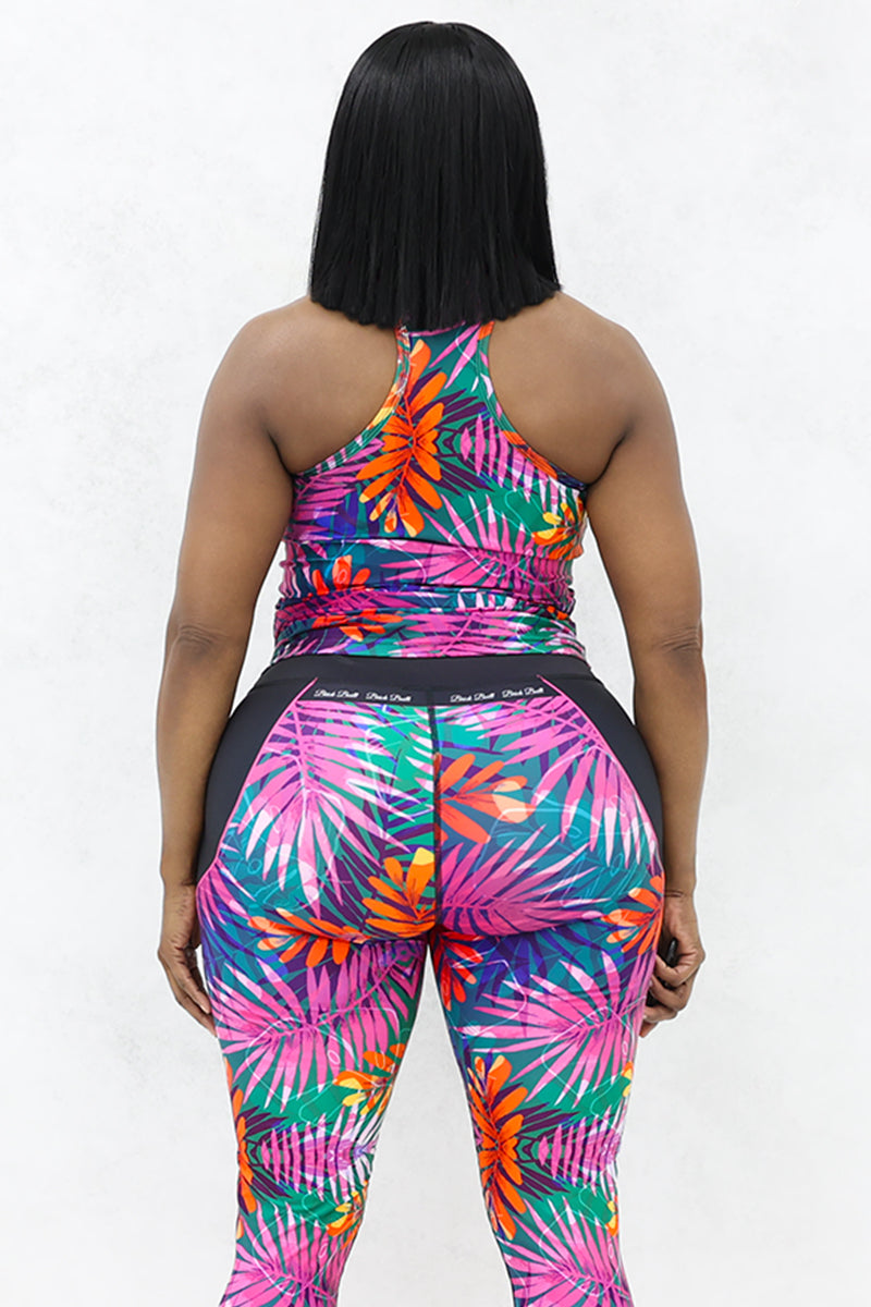 A woman wearing pink tank top and black floral print tights.