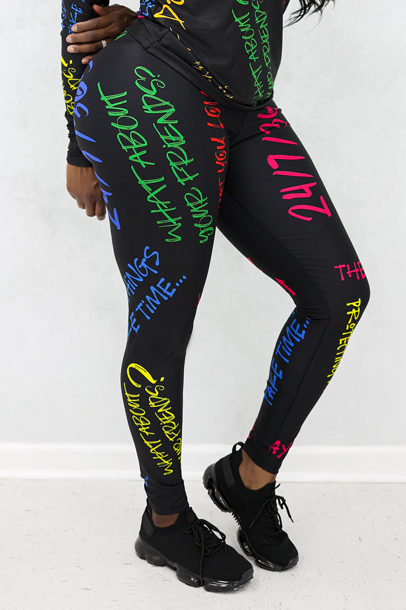 A woman wearing Quote Tights in black with multi-colored inspiring quotes, designed with durable, stretchy fabric and a continuous drawstring for comfort during workouts.