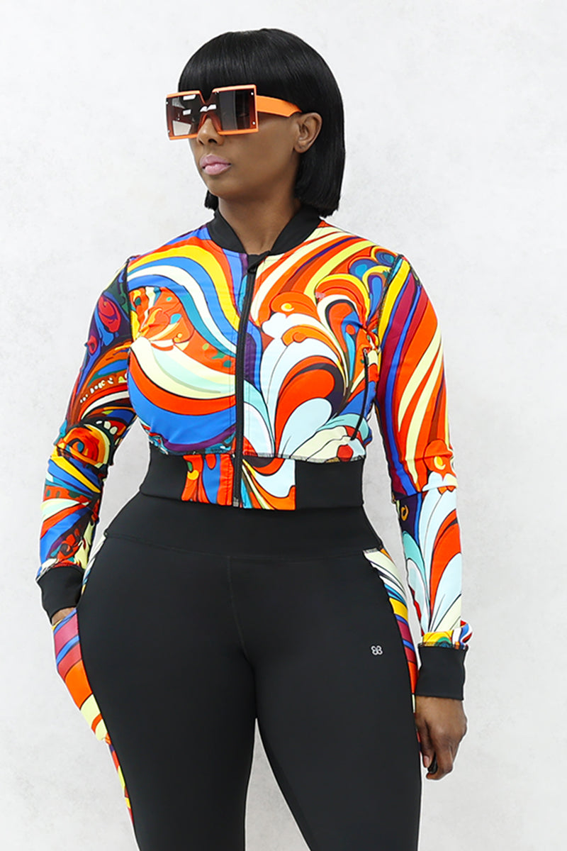 A woman wearing a multi-colored Slit Back Long Sleeve top with vibrant swirl patterns, featuring a snug fit and stylish design ideal for workouts or casual outings.