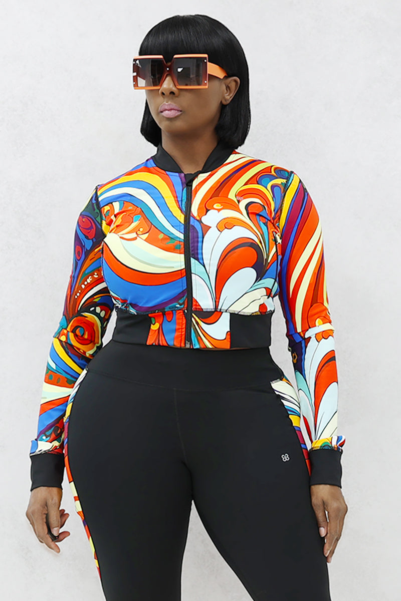 A woman wearing a multi-colored Slit Back Long Sleeve top with vibrant swirl patterns, featuring a snug fit and stylish design ideal for workouts or casual outings.