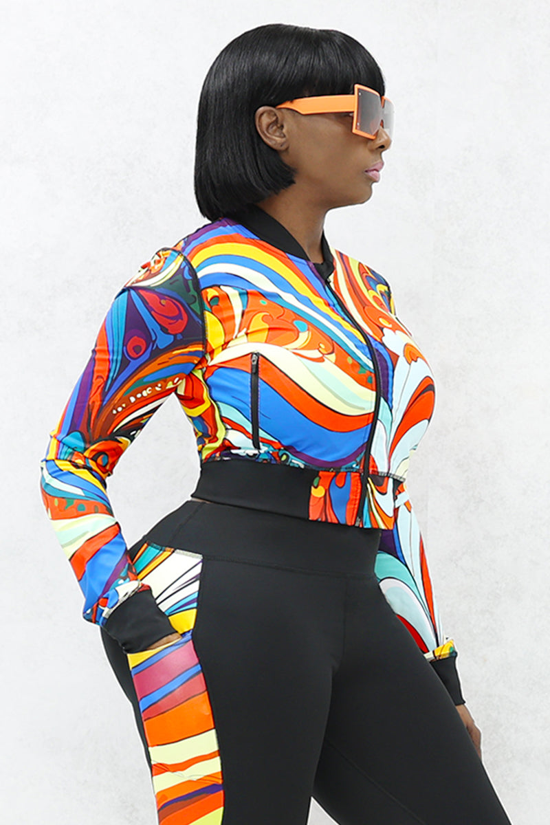 A woman wearing a multi-colored Slit Back Long Sleeve top with vibrant swirl patterns, featuring a snug fit and stylish design ideal for workouts or casual outings.