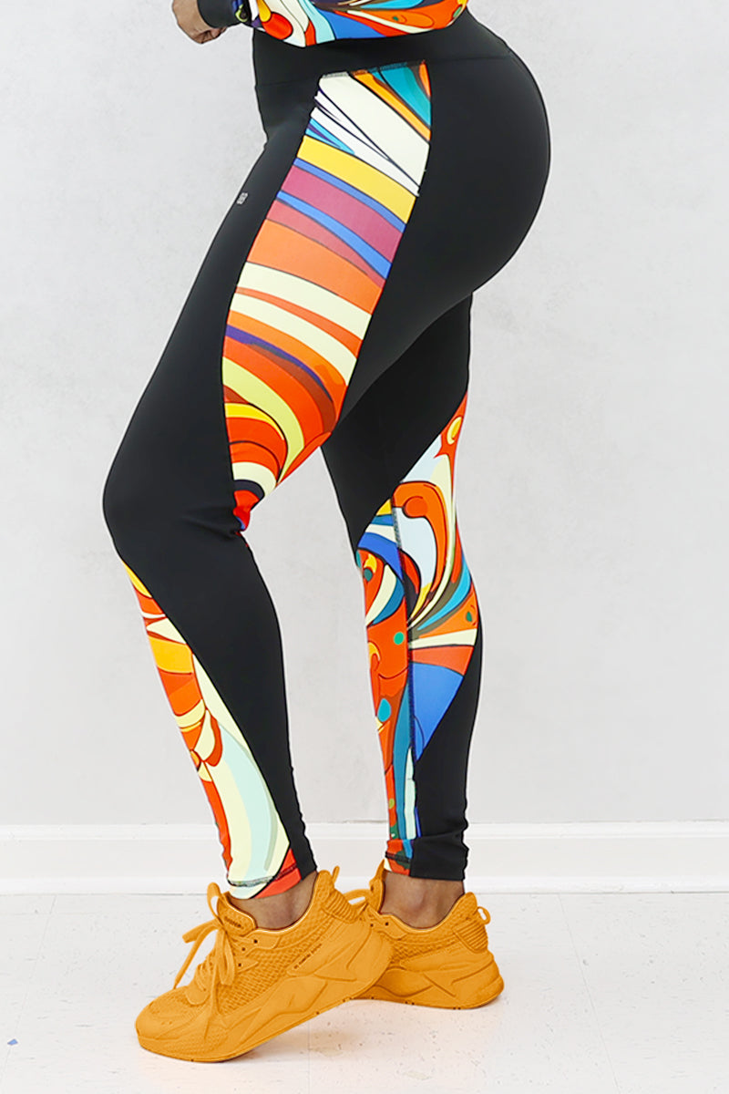 A woman wearing multi-colored Soul Train Tights featuring sleek black fabric with vibrant retro patterns, designed for comfort and performance during workouts or everyday activities.