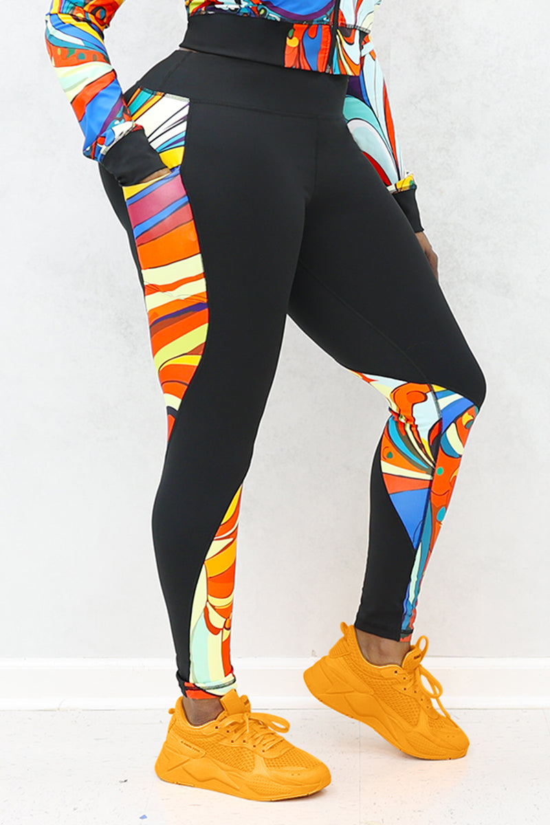 A woman wearing multi-colored Soul Train Tights featuring sleek black fabric with vibrant retro patterns, designed for comfort and performance during workouts or everyday activities.