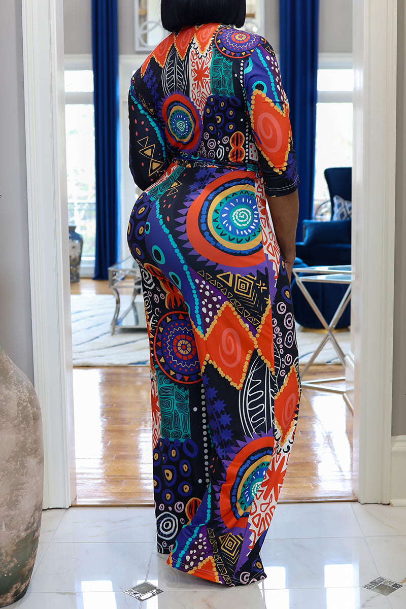 A woman wearing colorful patterned tribal jumpsuit standing in a room with blue decor.