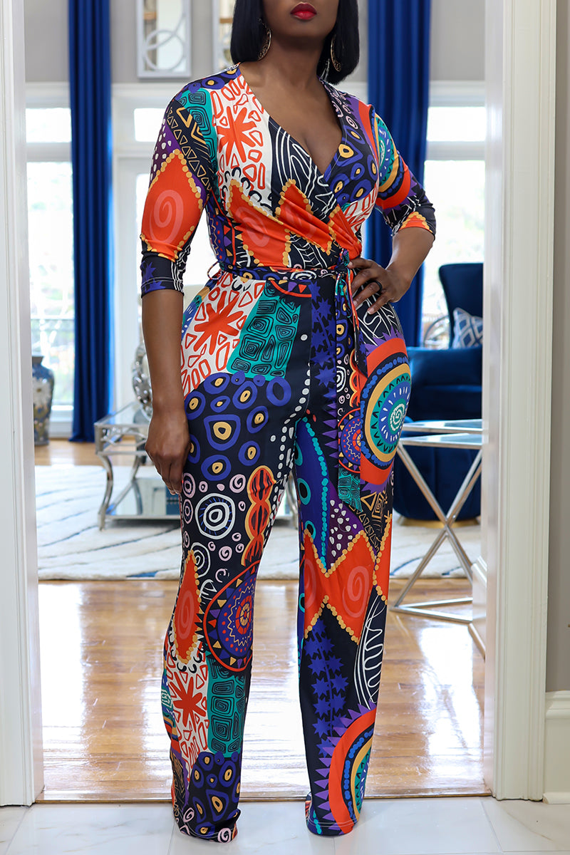 A woman wearing colorful patterned tribal jumpsuit standing in a room with blue decor.