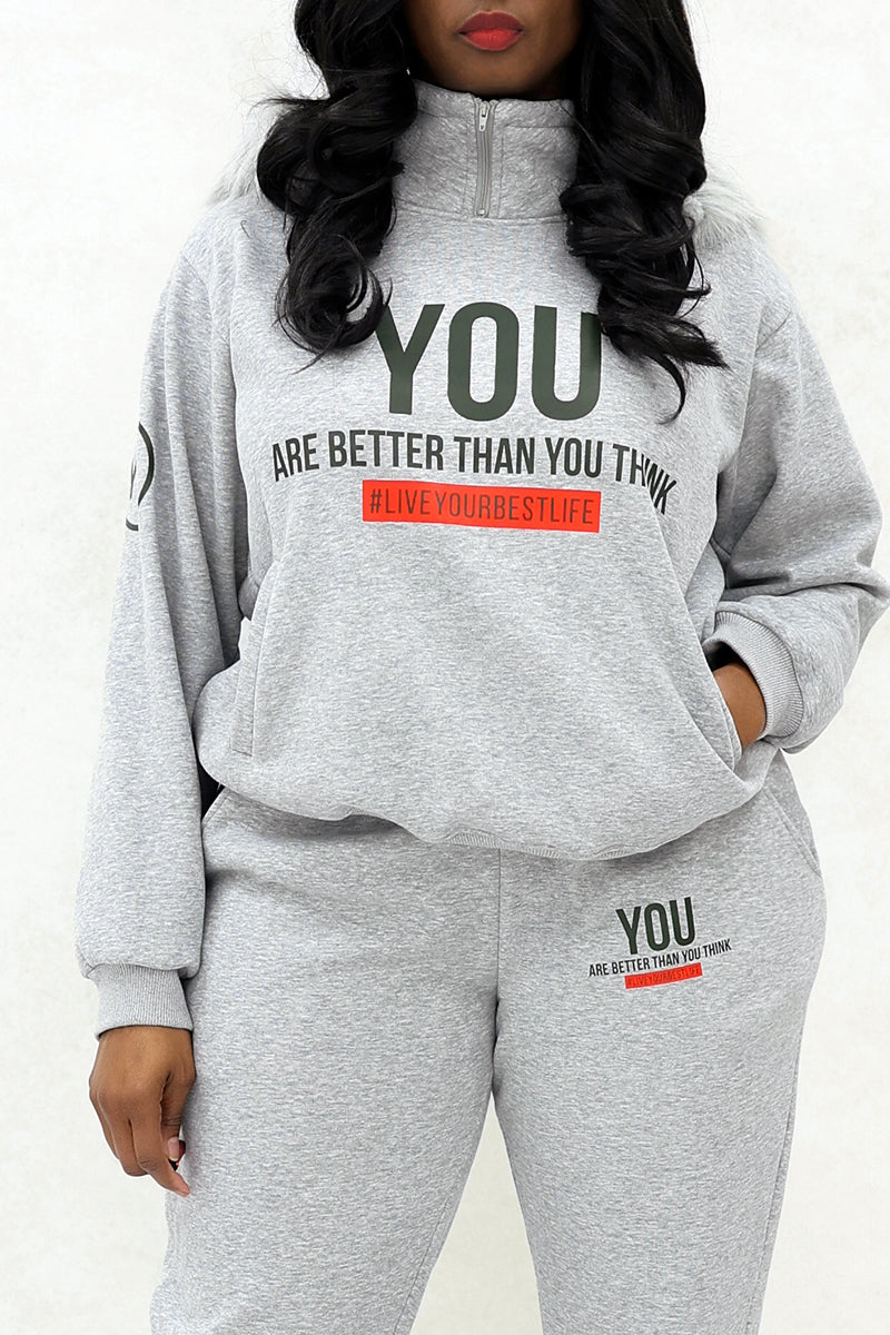 A woman wearing white fur-lined hood, "YOU" Fur hoodie and joggers with pockets.