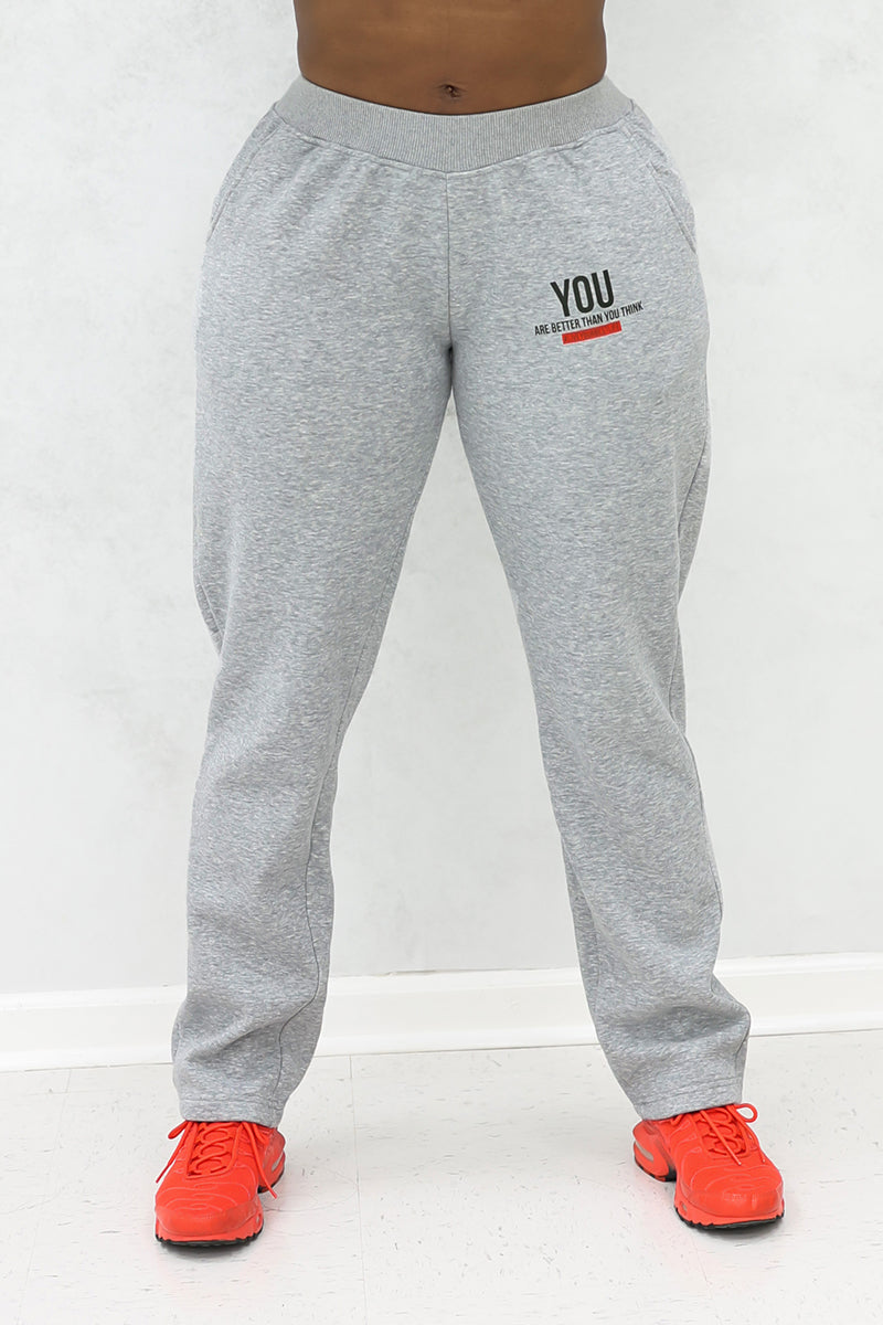 A woman wearing gray jogger pants with pockets and red shoes.