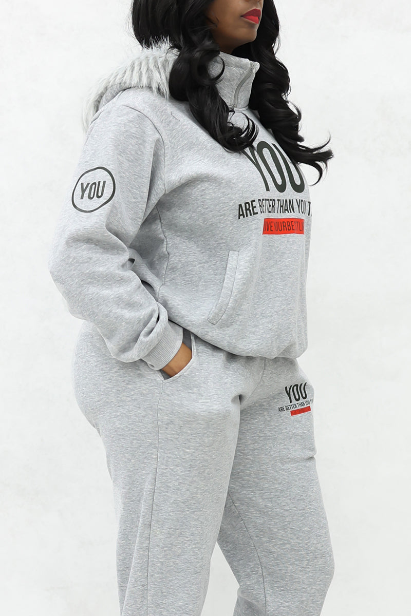 A woman wearing white fur-lined hood, "YOU" Fur hoodie and joggers with pockets.