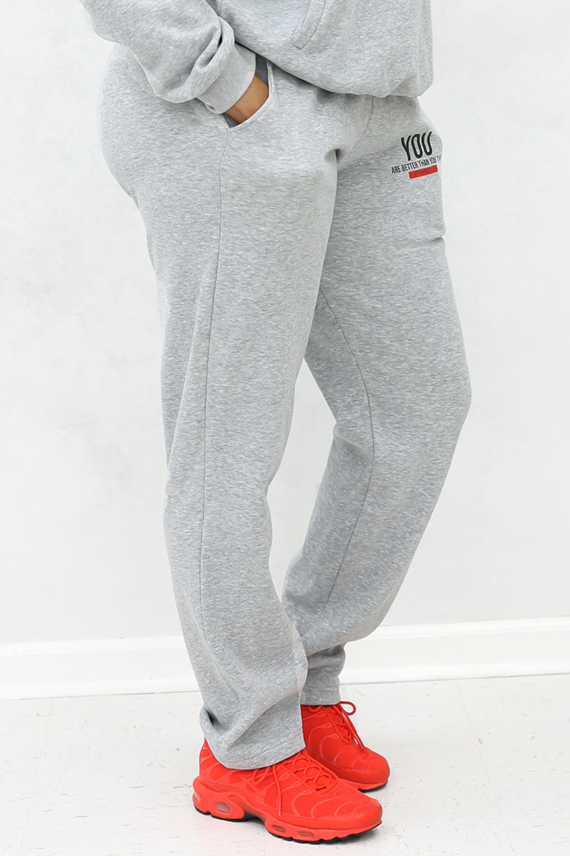 A woman wearing gray jogger pants with pockets and red shoes.