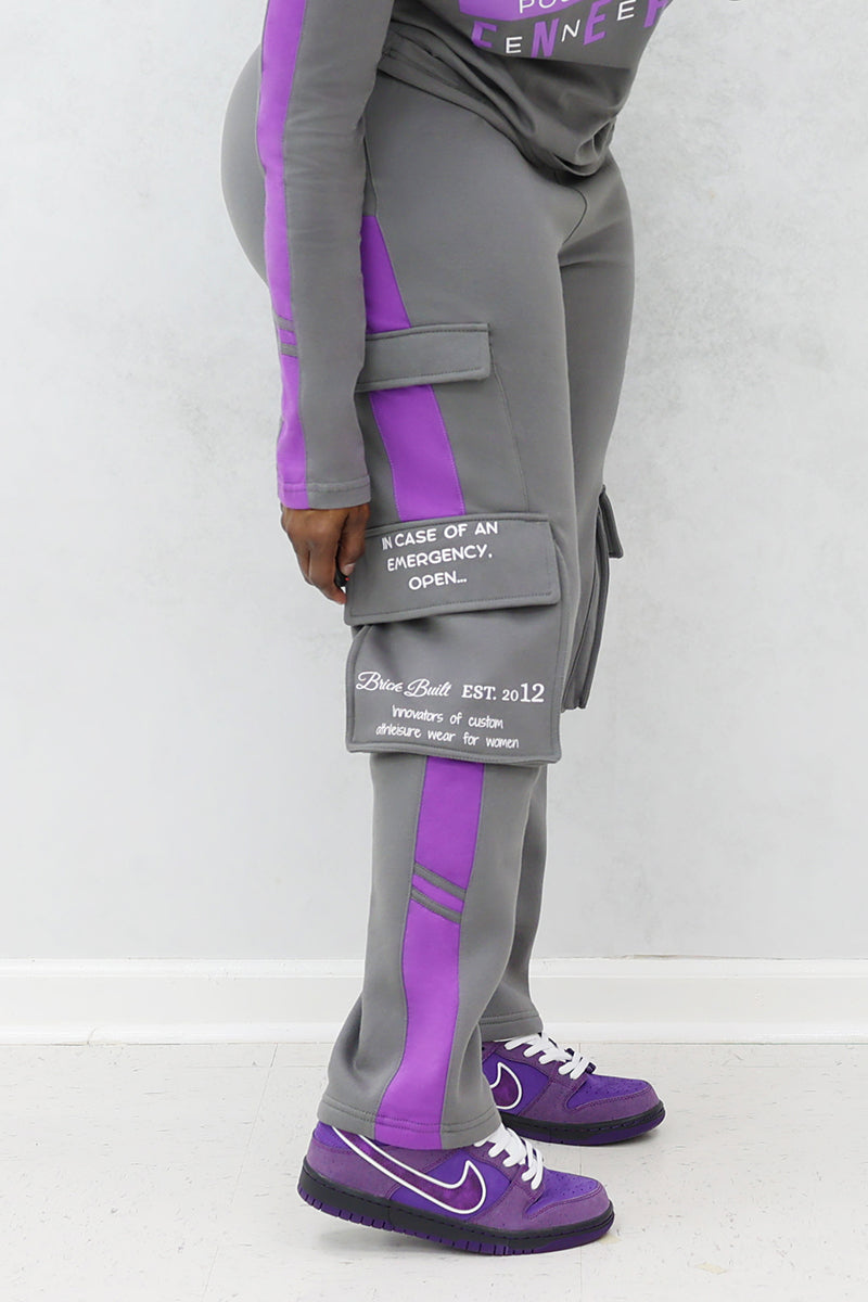 A woman wearing gray and purple cargo joggers with pockets and purple Nike shoes