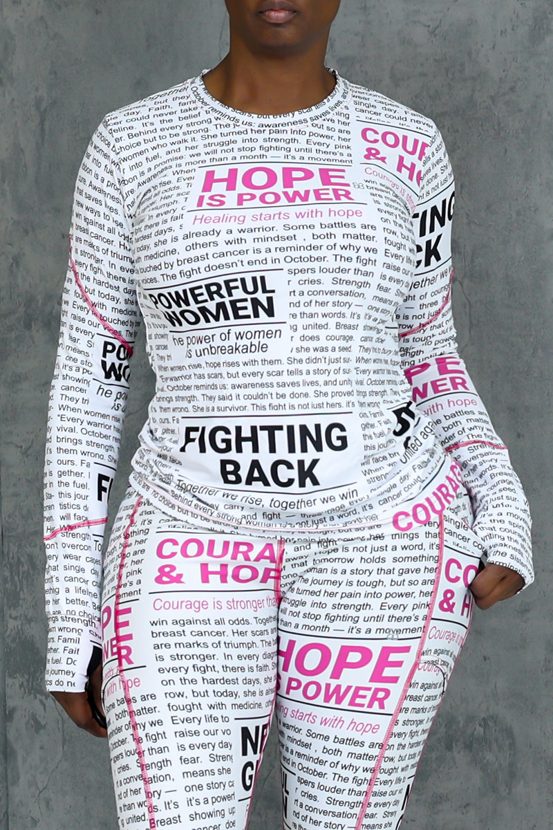 A person stands against a gray background wearing the Pink News Long Sleeve T-shirt, featuring black text and bold pink phrases like “HOPE IS POWER” and “FIGHTING BACK,” made from moisture-wicking fabric for comfort.