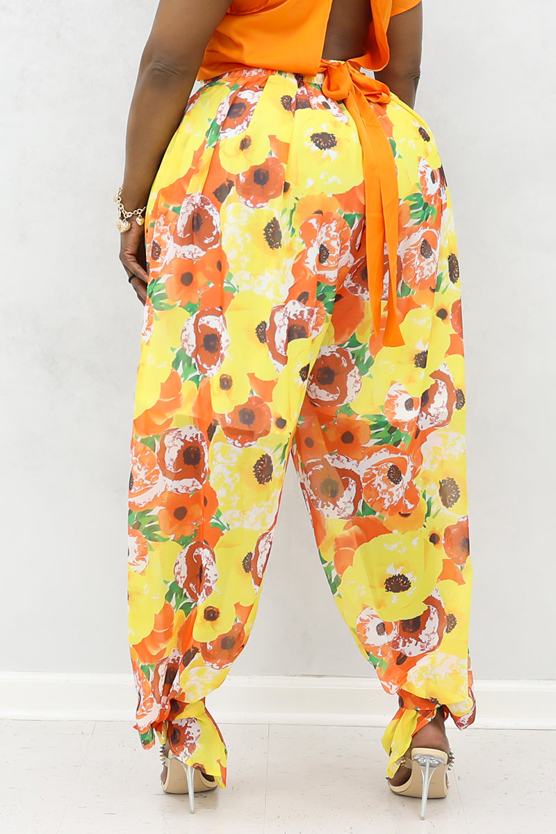 A woman wearing yellow and orange floral poppies tie ankle pants with heels.