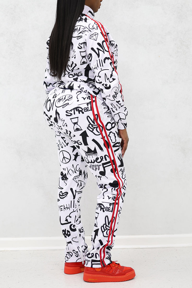 A woman wearing graffiti-print tracksuit with red stripes and shoes.