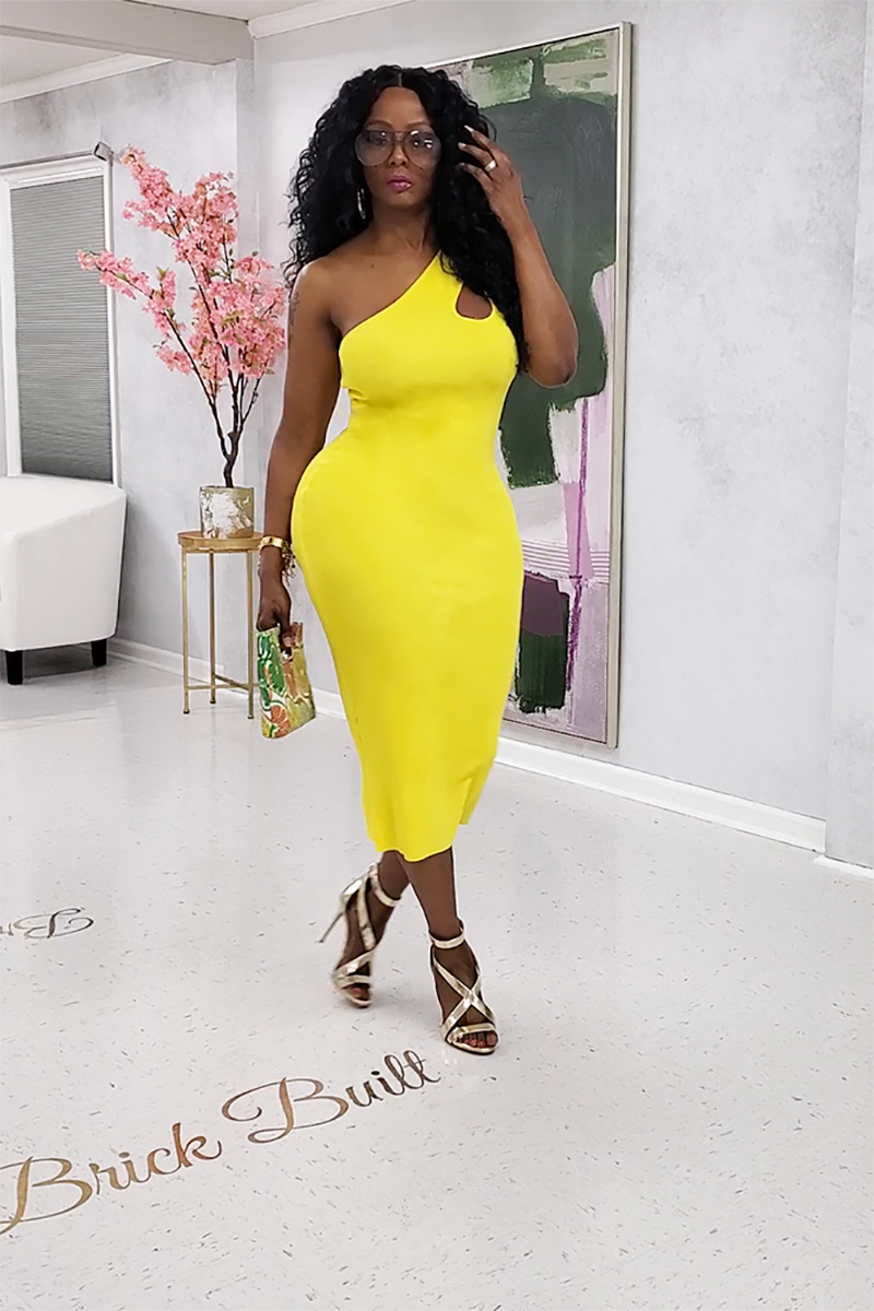 A woman wearing the Keyhole Body Dress in vibrant yellow, featuring a fitted silhouette and exposed shoulders for a stunning look.
