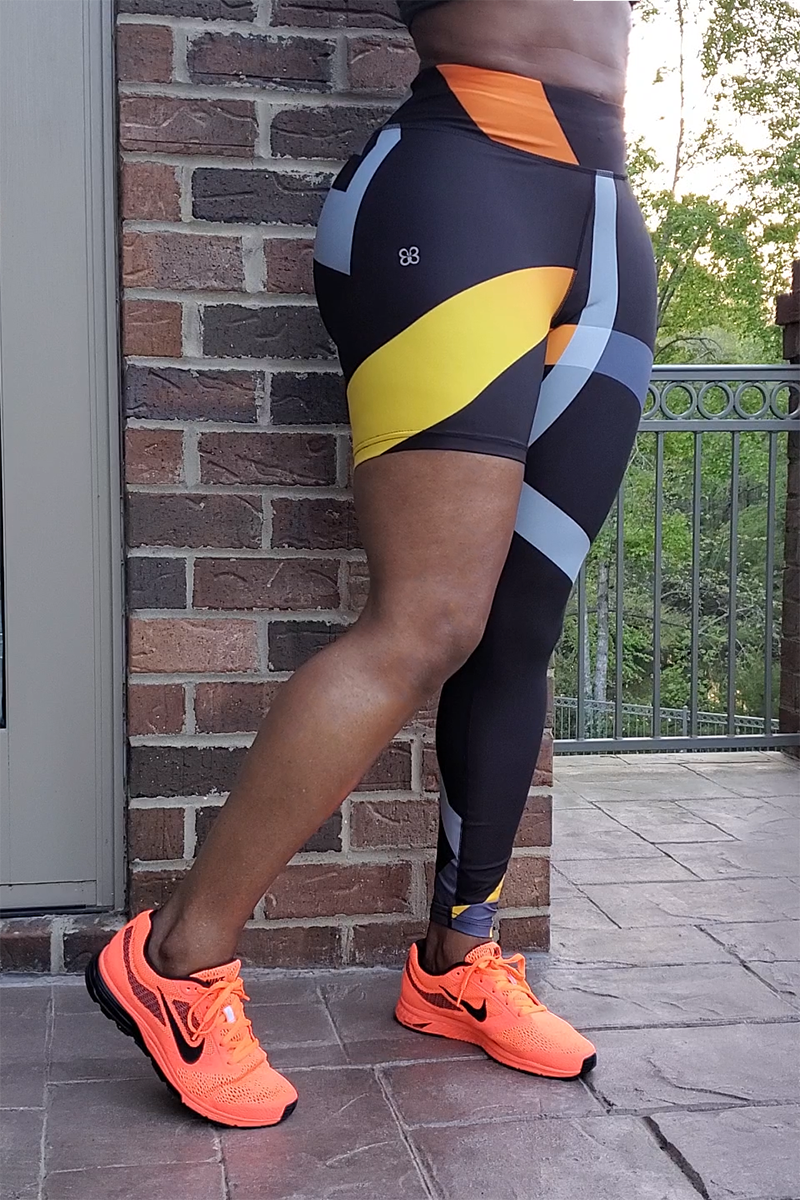 A woman wearing unique one-legged tights featuring vibrant ombre colors in orange-yellow, designed for individuality and comfort during workouts.
