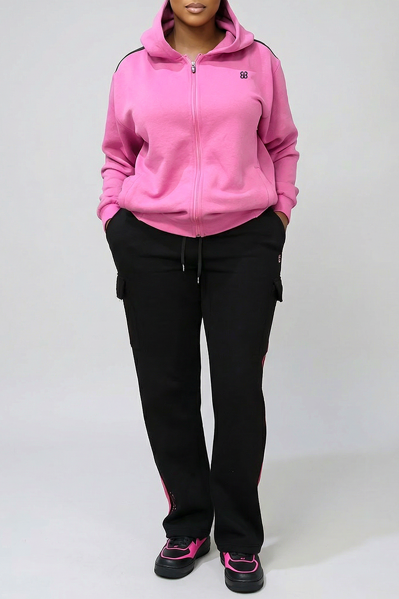 A person stands with hands in their pockets, wearing a pink fleece-lined zip-up hoodie, Two Stripe Cargo Pants, and black sneakers with pink accents against a plain light background.