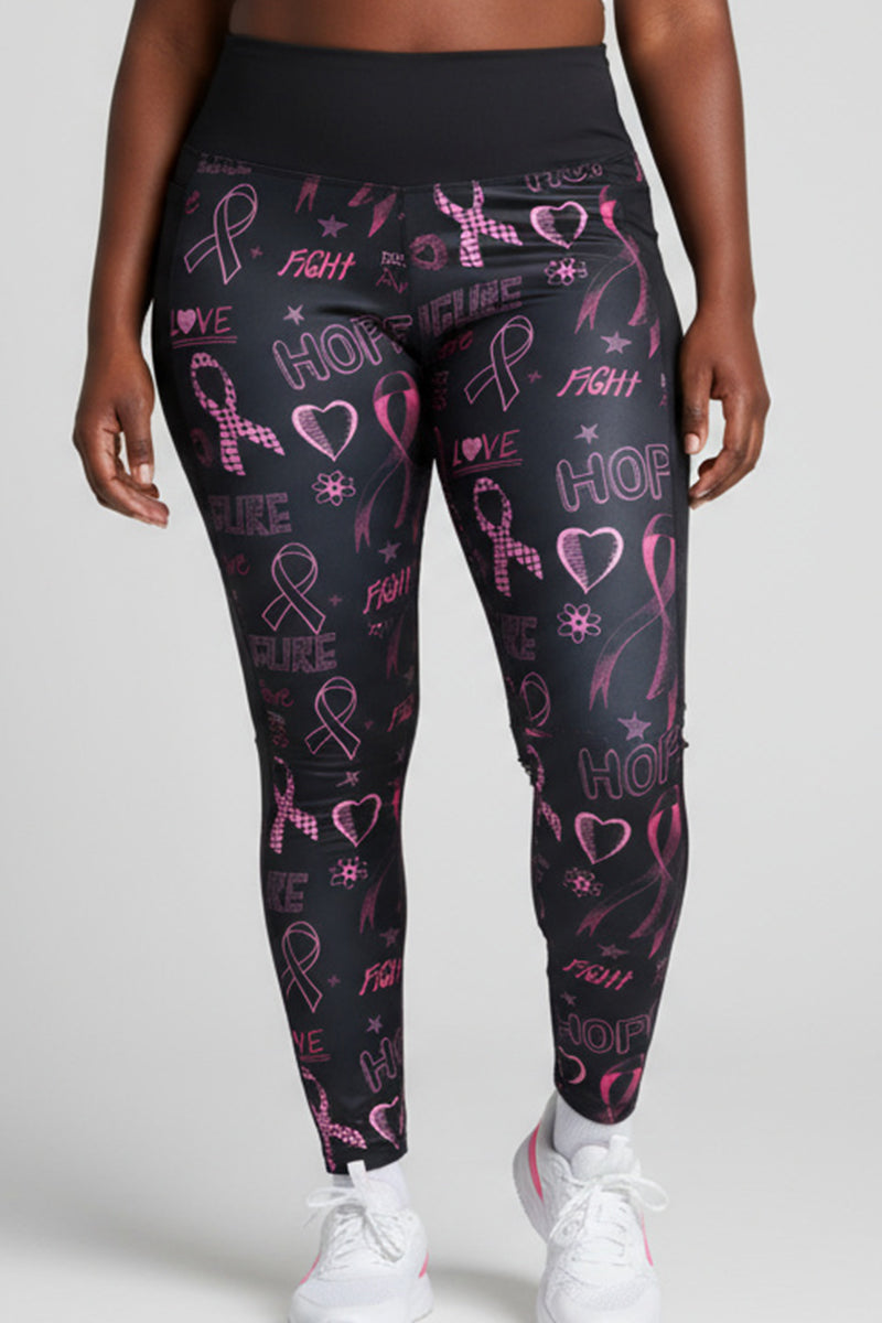 A person wears black-pink Hope Tights (SAMPLE) featuring breast cancer awareness designs—pink ribbons, hearts, stars, and words like hope, fight, love, and cure—paired with white sneakers.