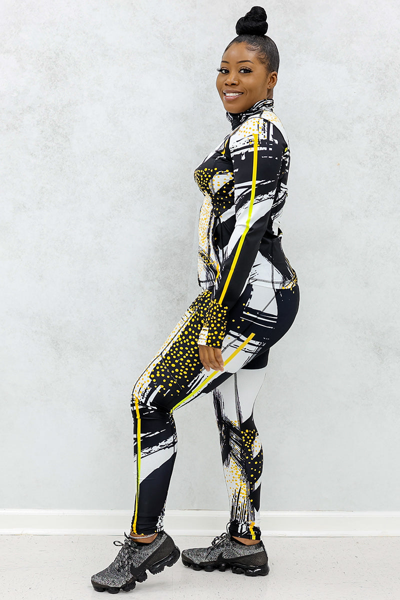 a woman wearing a pair of fitness leggings printed with a black, gold, and white abstract design. 