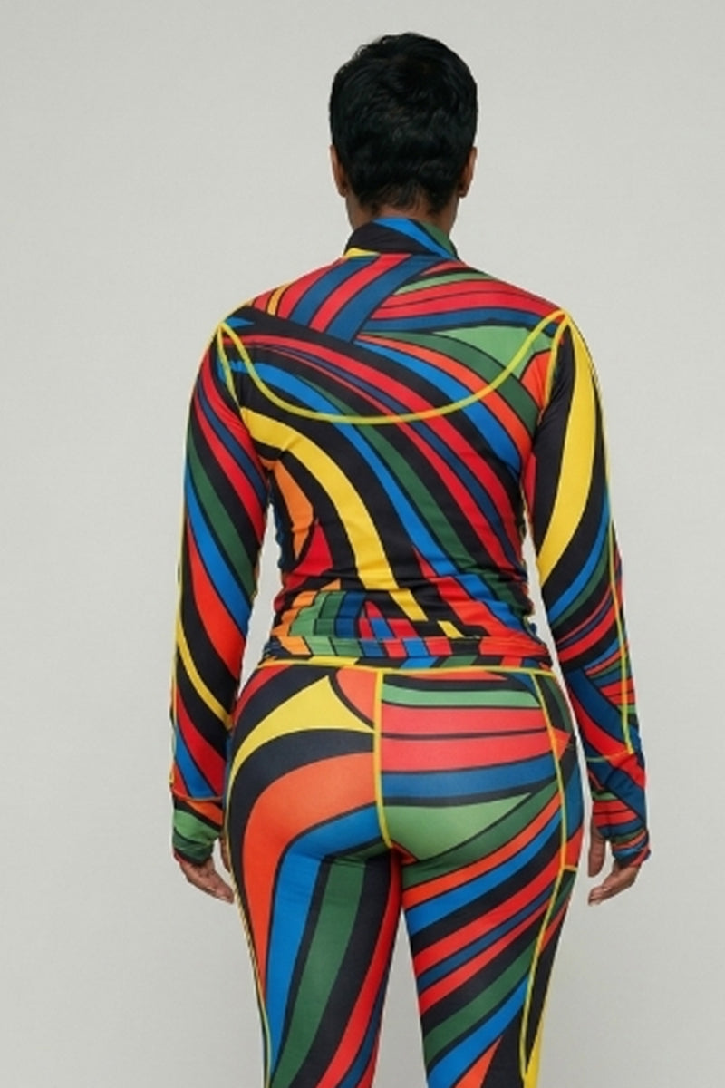 A person faces away from the camera, wearing the Color Riot Jacket—a fitted, long-sleeve top with thumbhole sleeves—and pants with a vibrant geometric swirl pattern in red, yellow, blue, green, and black against a plain light background.