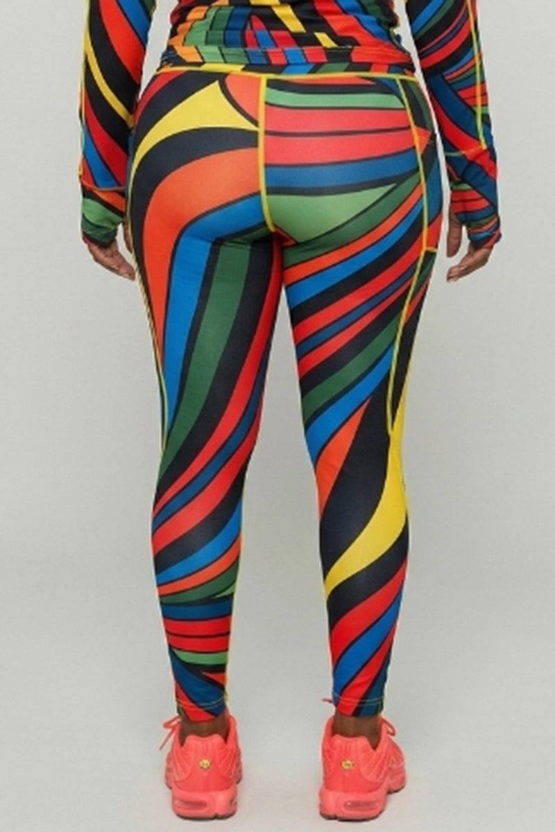 Photographed from behind, a person wears Color Riot Tights—long-sleeve top, vibrant wavy stripes, 4-way stretch for fit and comfort. Pink athletic shoes complete the look against a plain, light background.