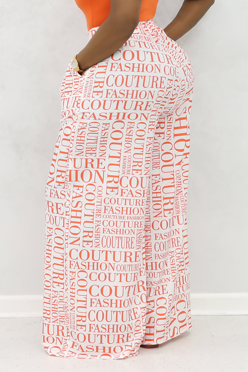 A woman wearing white and orange couture palazzo pants with a stylish design.