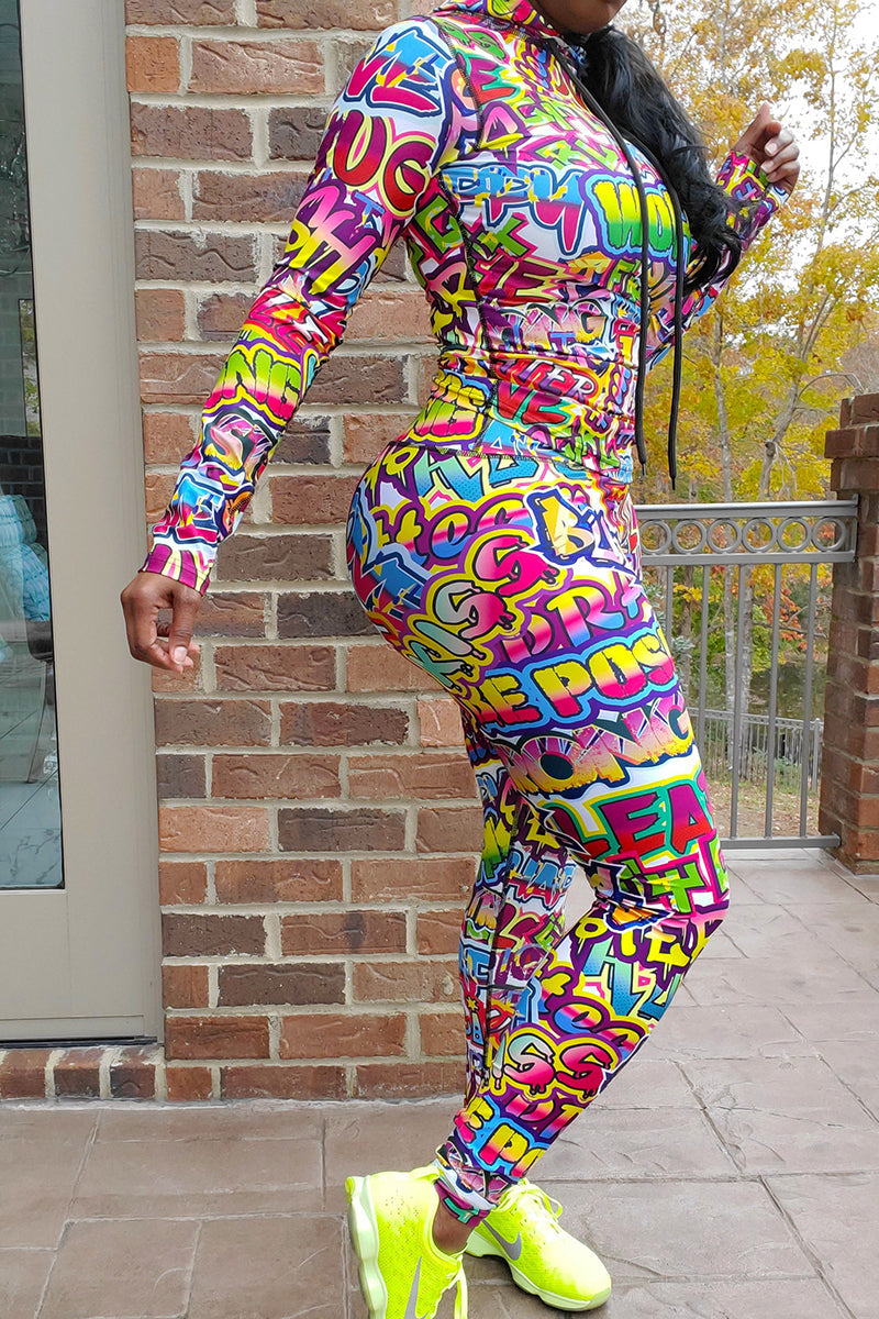 A woman wearing a multi-colored Graffiti hooded pullover with a unique design, perfect for workouts and casual wear.