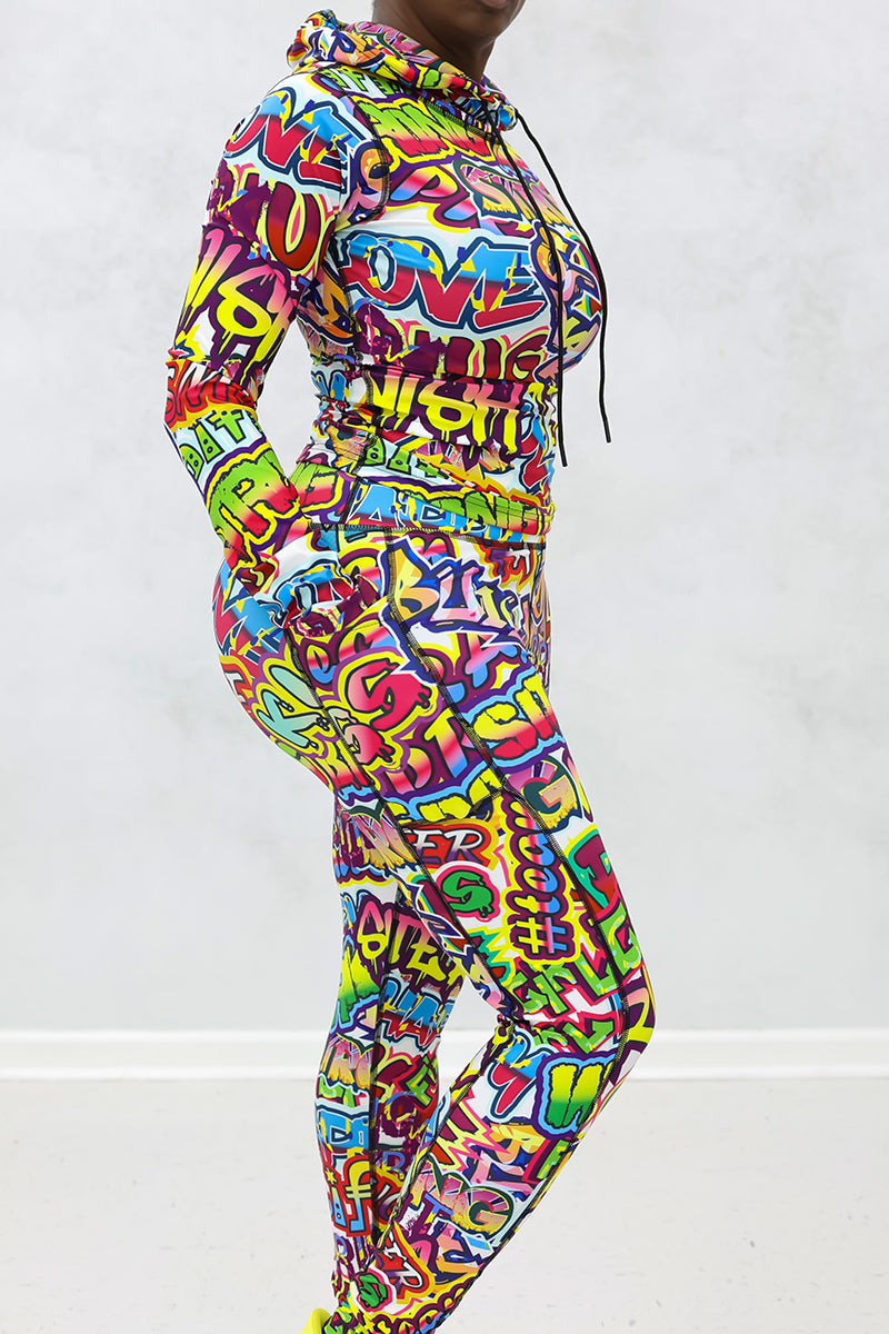 A woman wearing a multi-colored Graffiti hooded pullover with a unique design, perfect for workouts and casual wear.