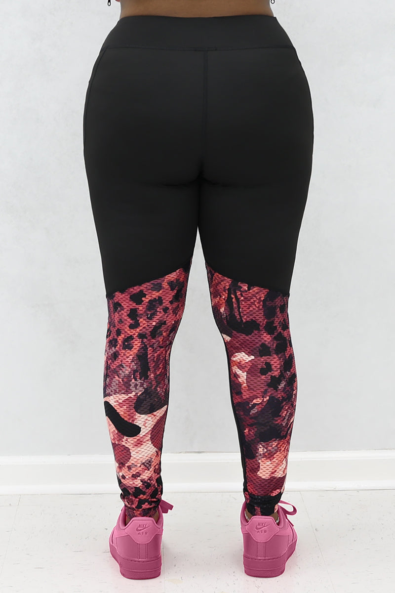 A woman wearing black and pink Graphic tights featuring printed panels and a continuous drawstring for a secure fit.