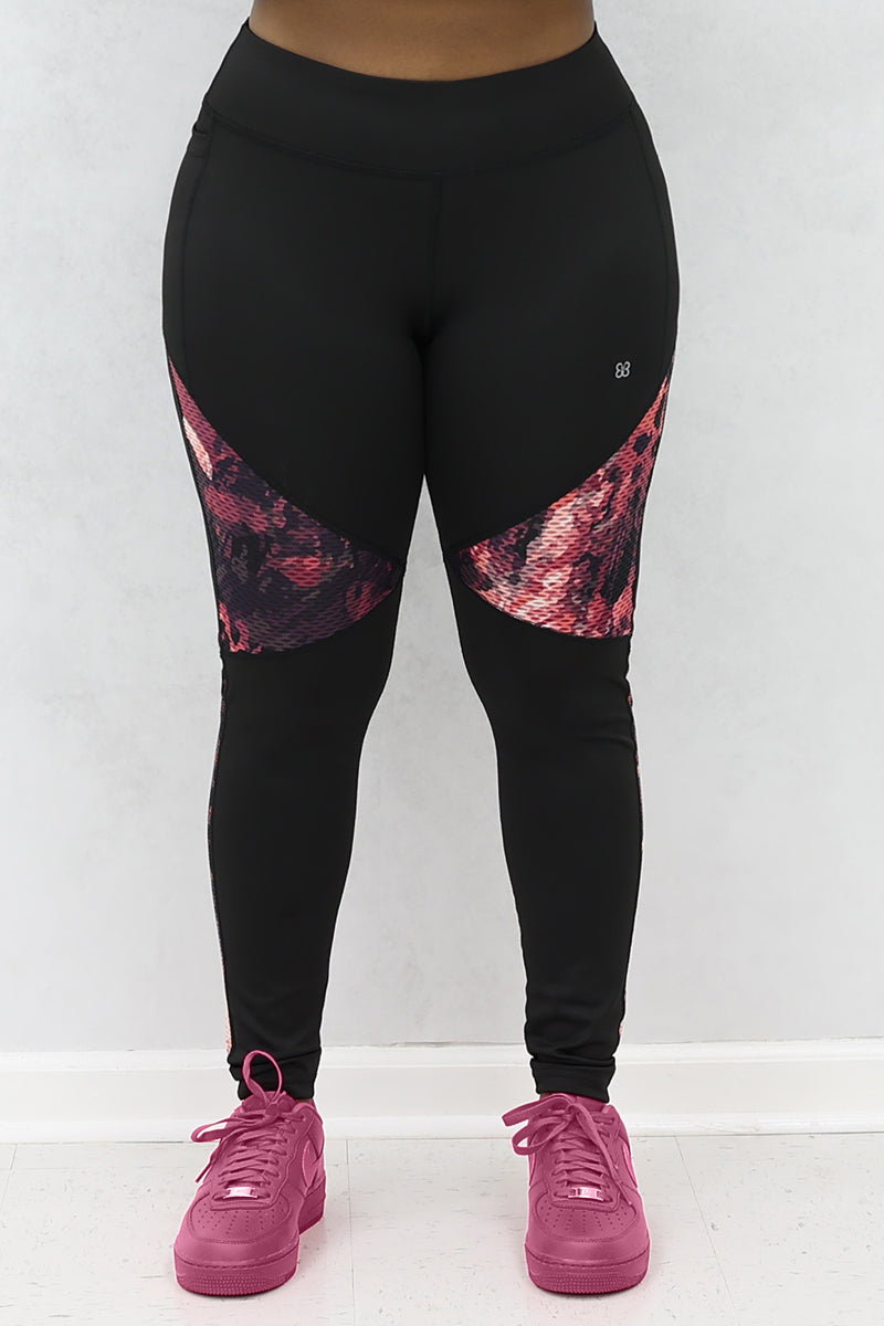 A woman wearing black and pink Graphic tights featuring printed panels and a continuous drawstring for a secure fit.