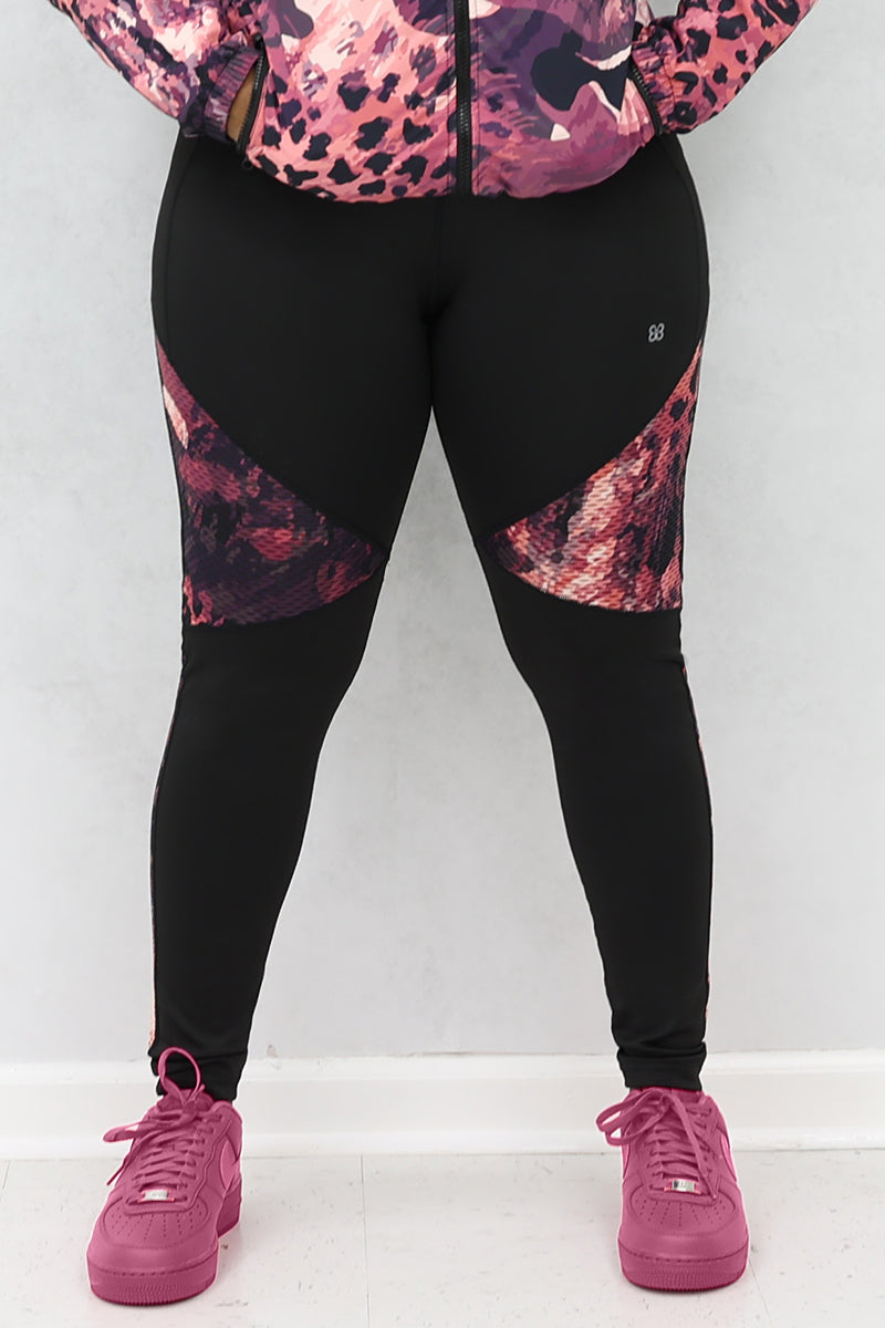 A woman wearing black and pink Graphic tights featuring printed panels and a continuous drawstring for a secure fit.