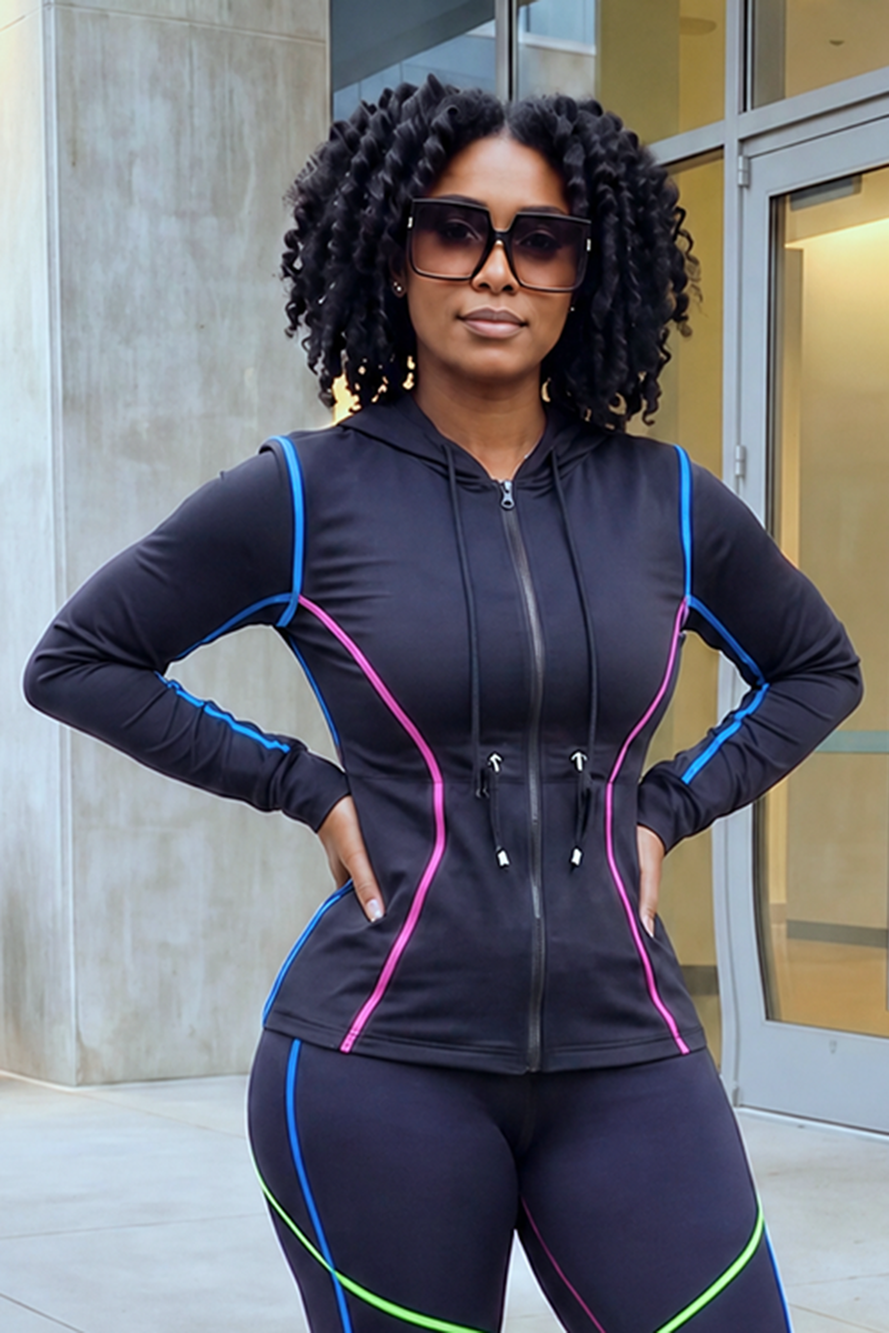 A woman with curly hair stands outside a building, hands on her hips, wearing sunglasses and the Multi-Stitching Long Sleeve Jacket 1st Edition—a black, stretchy jacket featuring pink and blue piping—paired with matching leggings.