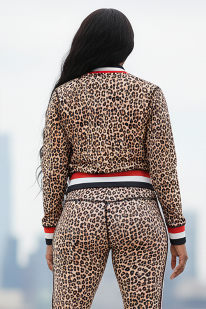 A person with long, wavy black hair is seen from behind, wearing the Ona Bomber Jacket in leopard print with red, white, and black striped trim. The blurred background reveals city buildings.