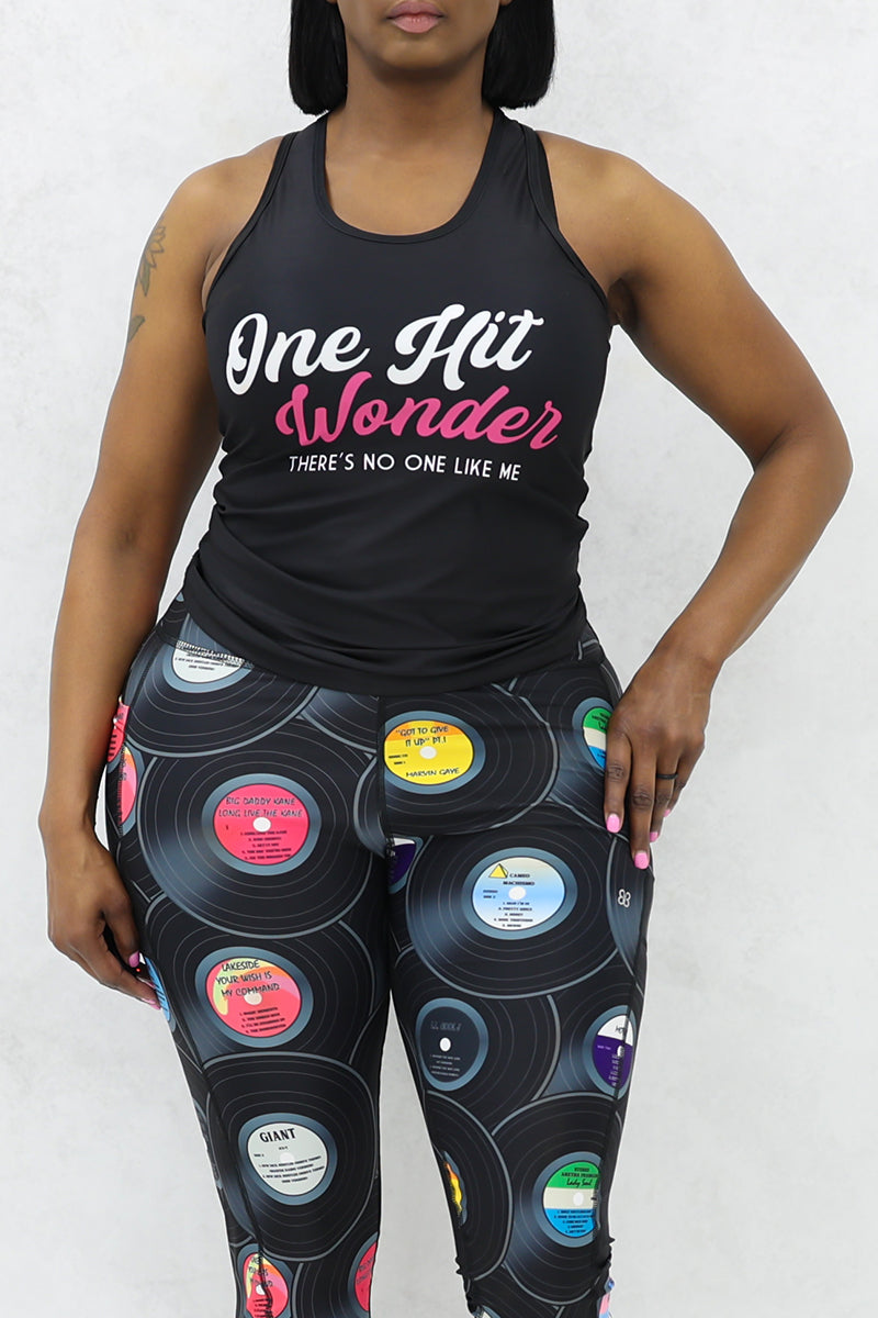 A woman wearing a black One Hit Wonder Tank, made of stretchy polyester and spandex, offering a sleek and comfortable fit.