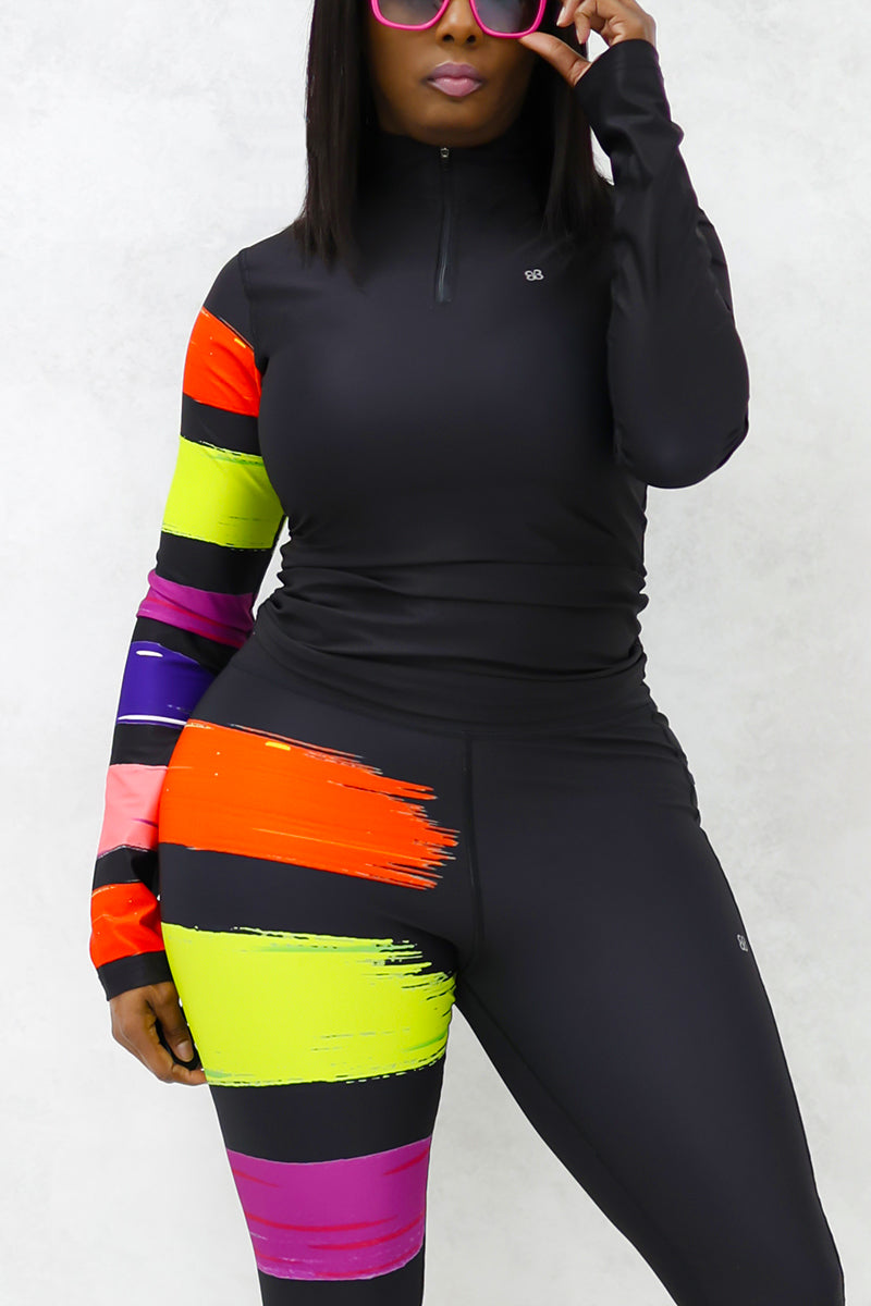 A woman wearing the Paint Strokes Half-Zip Pullover in vibrant multi colors, featuring a half zipper and a pocket on the left leg, showcasing a stylish blend of black, orange, lime, and purple.