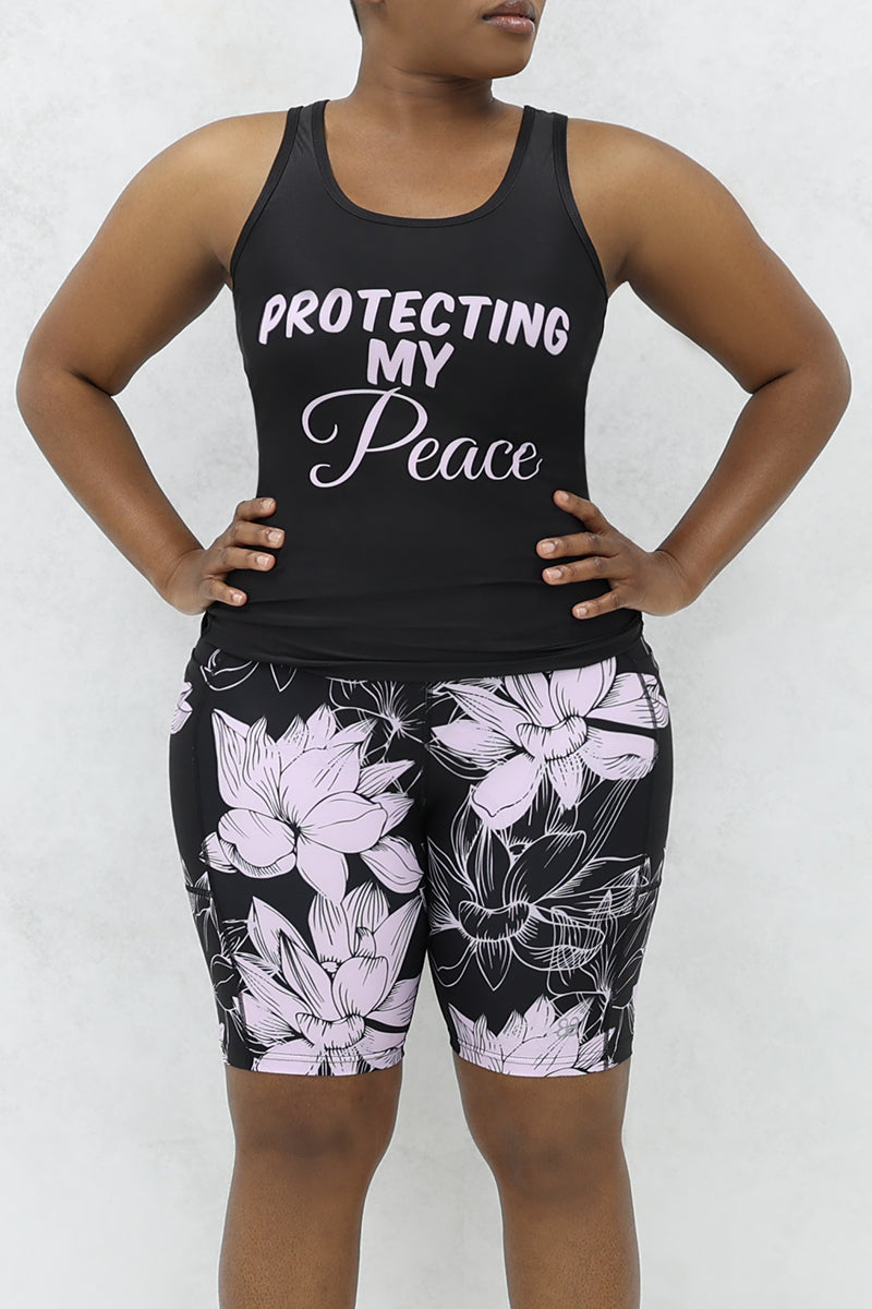 A woman wearing Lavender Floral Shorts, showcasing a stylish workout look. The lightweight and breathable shorts feature a vibrant lavender floral design, perfect for staying active and fashionable during workouts.