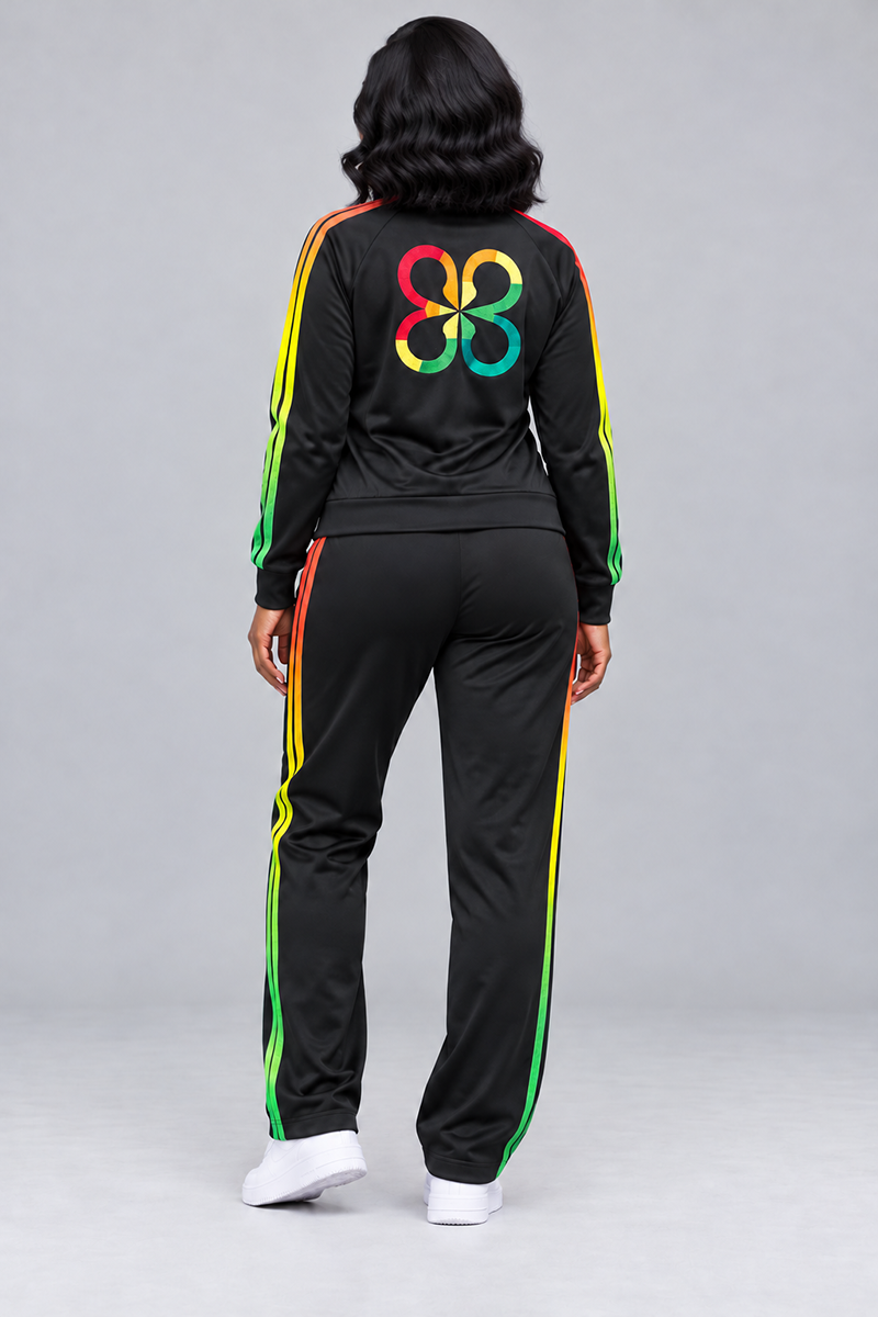 A person in a relaxed, loose-fit black Juneteenth Track Jacket and matching track pants with red, yellow, and green stripes, featuring a multicolored, four-lobed emblem on the back of the jacket.