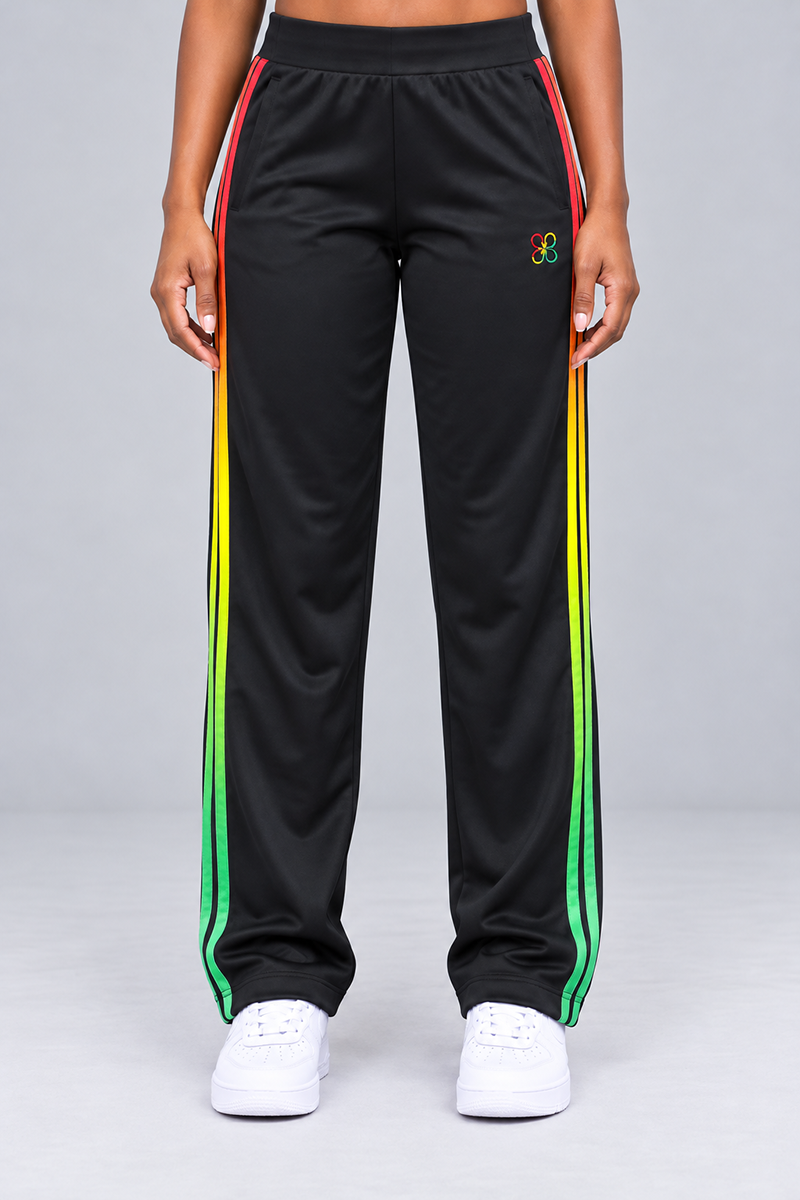Juneteenth Sweatpants in a relaxed, loose-fit black design, featuring a red, yellow, and green gradient stripe down each leg, an adjustable drawstring waistband, and a small flower-shaped logo on the left hip.